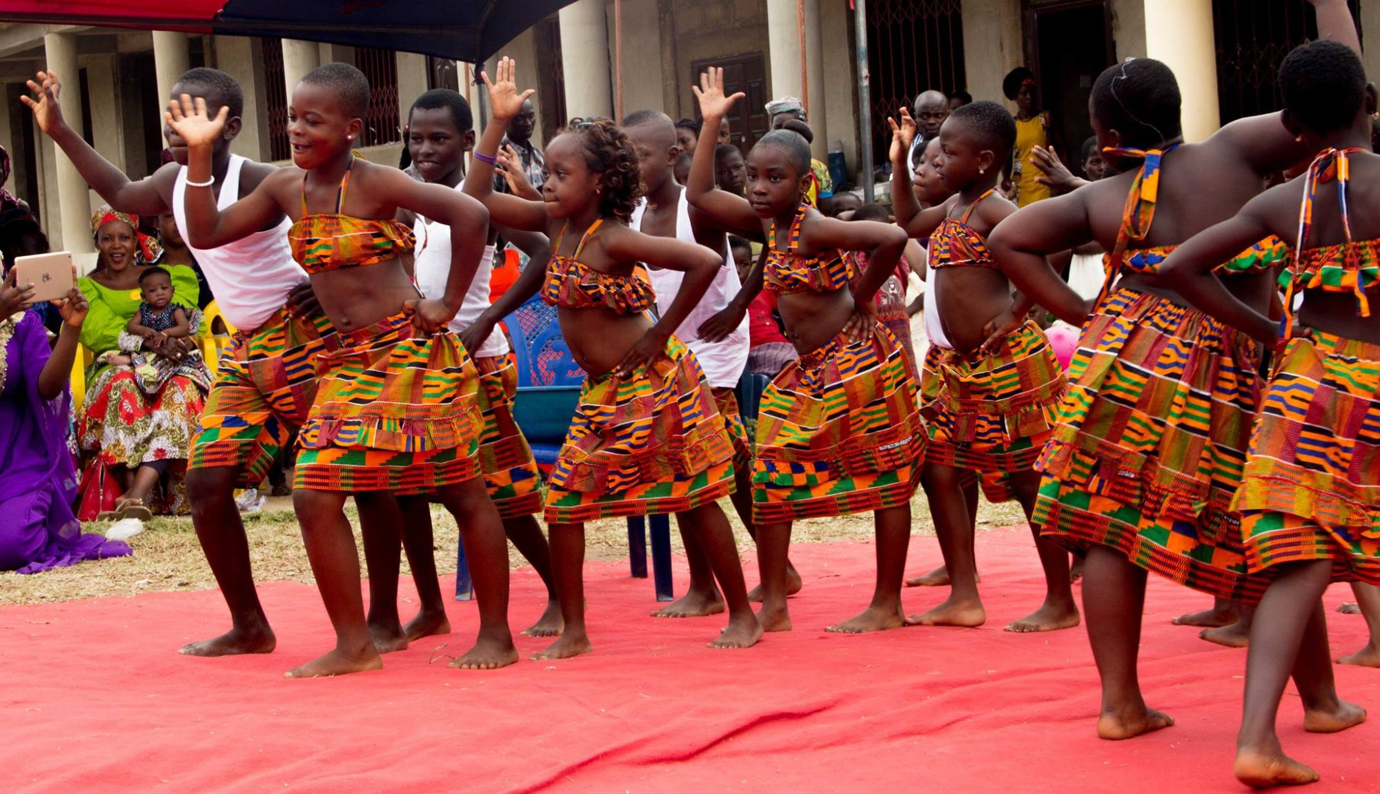 Students performing Ghanaian traditional dance in kente attire